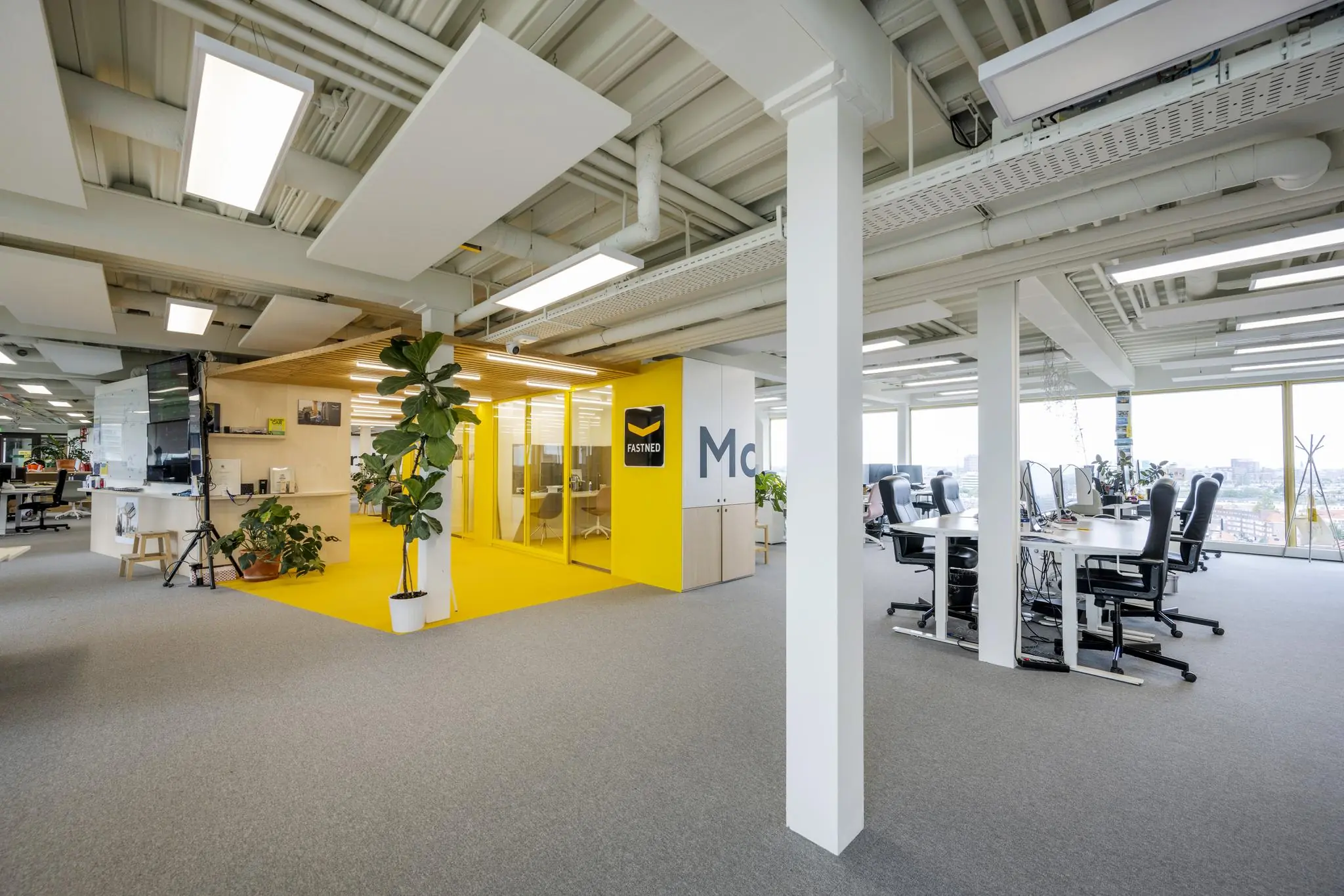 Modern en licht kantoorpand van Fastned aan de James Wattstraat met open werkplekken en een glazen vergaderruimte.